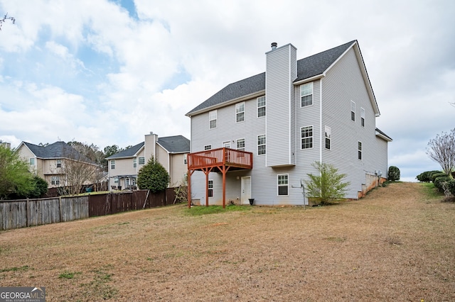 rear view of property with a yard, a wooden deck, a chimney, and fence