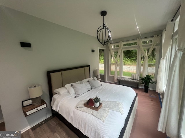 bedroom with a chandelier and dark wood-type flooring