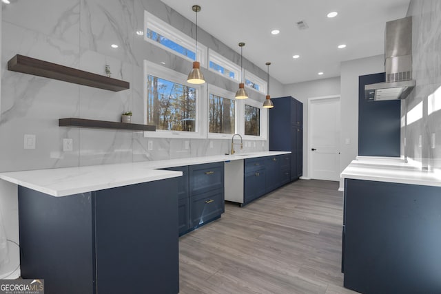 kitchen with ventilation hood, sink, blue cabinetry, light hardwood / wood-style floors, and hanging light fixtures