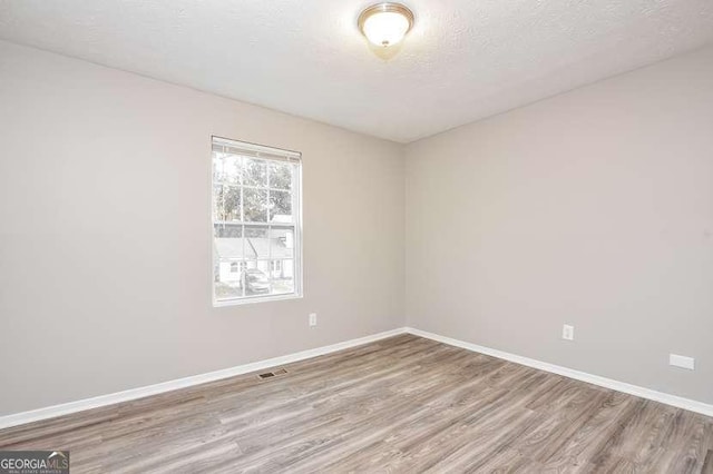 empty room featuring light hardwood / wood-style flooring and a textured ceiling