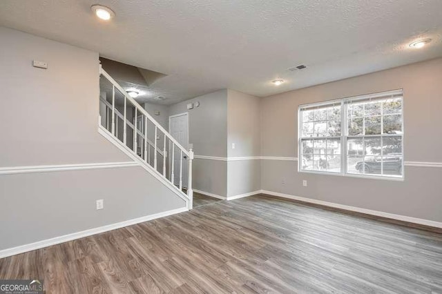 empty room featuring wood-type flooring and a textured ceiling