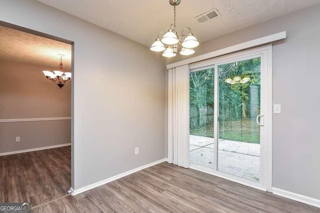 unfurnished dining area featuring dark hardwood / wood-style floors and a chandelier