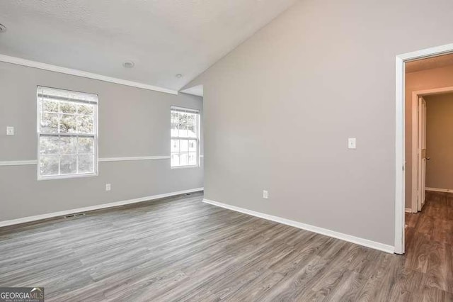 empty room featuring a wealth of natural light, hardwood / wood-style floors, and vaulted ceiling