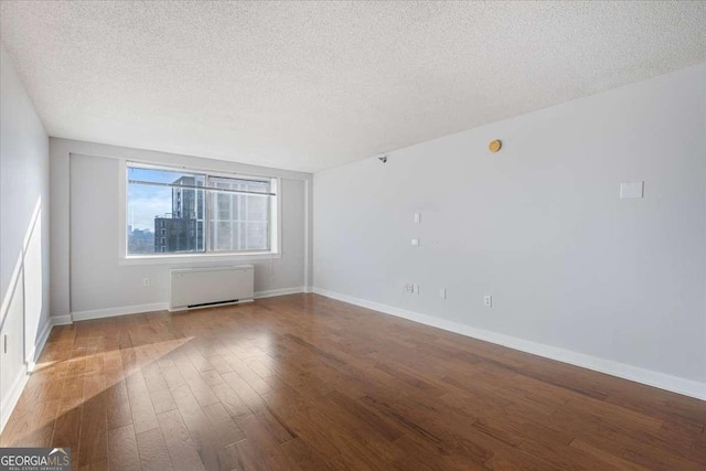 unfurnished room featuring radiator heating unit, a textured ceiling, and wood-type flooring