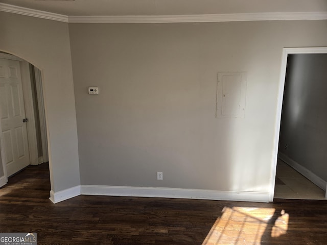 spare room featuring electric panel, crown molding, and dark wood-type flooring