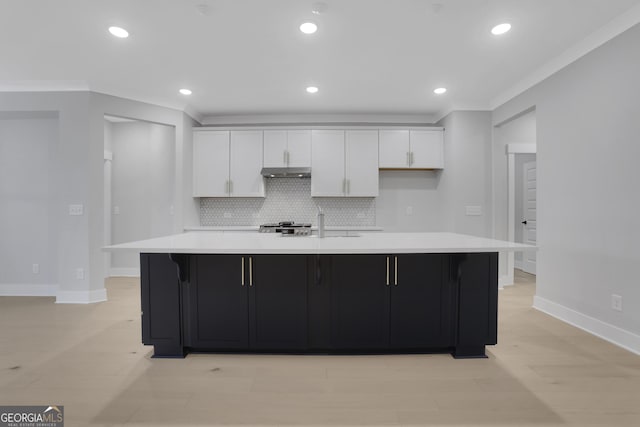 kitchen with white cabinets, decorative backsplash, crown molding, and a large island