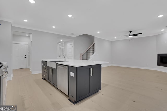 kitchen featuring a center island with sink, sink, ceiling fan, light wood-type flooring, and stainless steel appliances