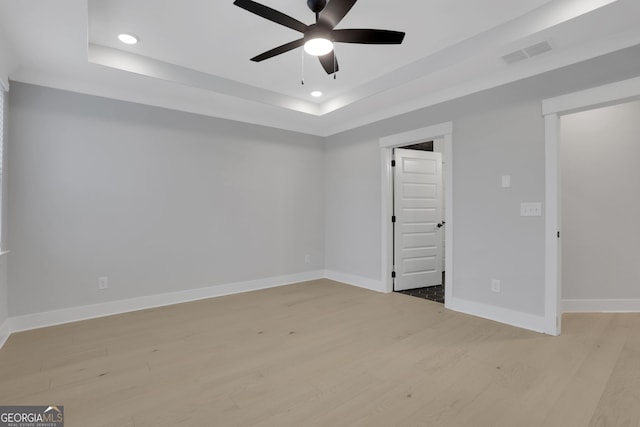 empty room featuring a tray ceiling, light hardwood / wood-style flooring, and ceiling fan