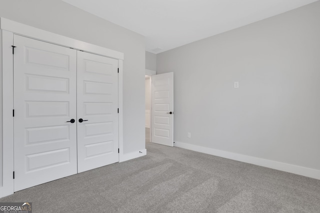 unfurnished bedroom with light colored carpet and a closet