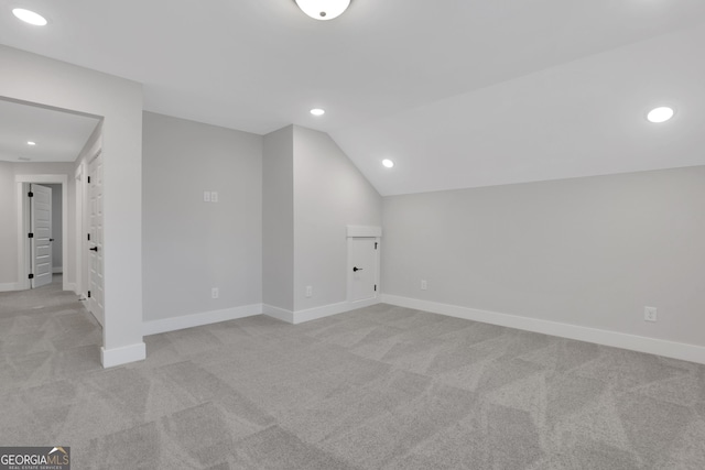 additional living space featuring light colored carpet and vaulted ceiling