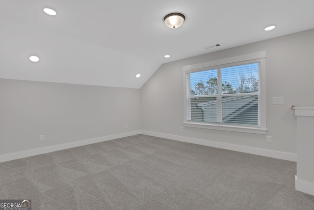 bonus room with light colored carpet and vaulted ceiling