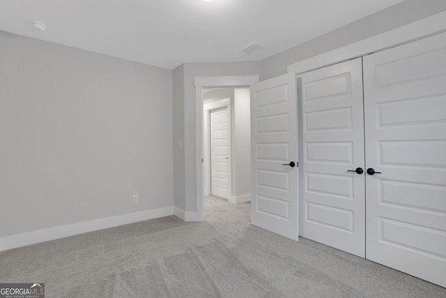 unfurnished bedroom featuring a closet and light colored carpet