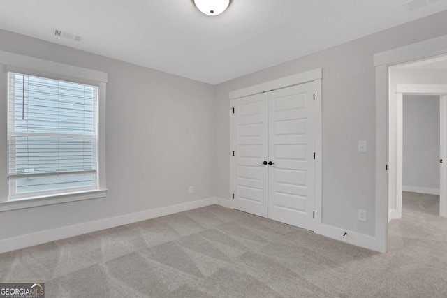 unfurnished bedroom featuring light colored carpet and a closet