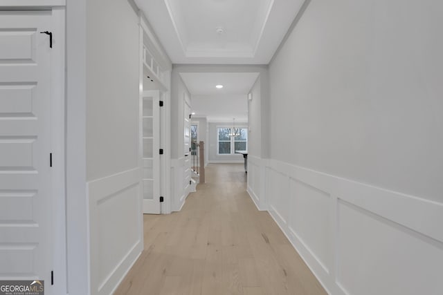 hall featuring a chandelier and light hardwood / wood-style floors