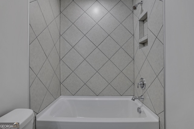 bathroom featuring toilet and tiled shower / bath