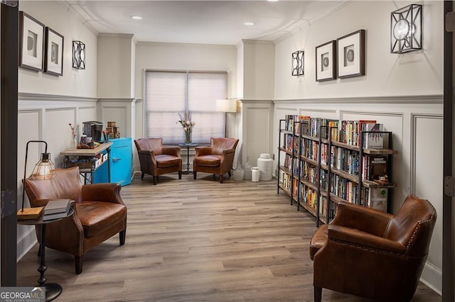 living area with light wood-type flooring and ornamental molding