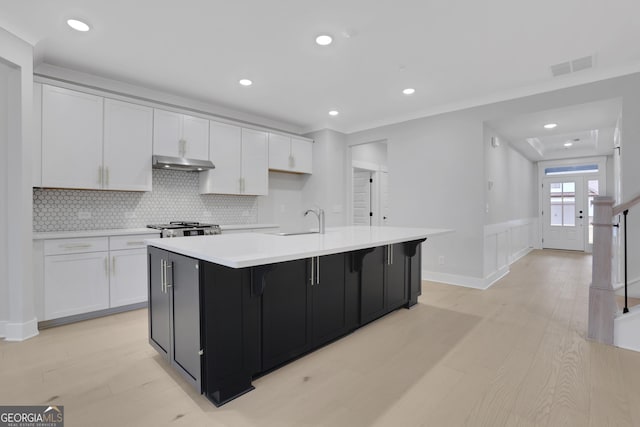 kitchen featuring white cabinets, light hardwood / wood-style floors, and an island with sink