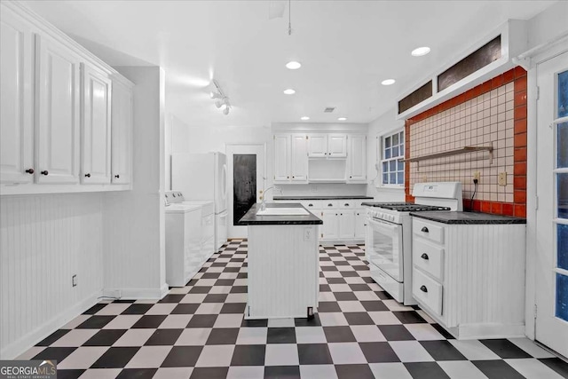 kitchen featuring a center island, white cabinets, washing machine and dryer, white gas range, and tasteful backsplash