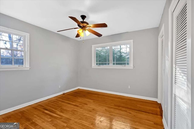 unfurnished bedroom featuring multiple windows, ceiling fan, and hardwood / wood-style floors