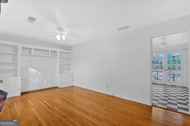 interior space with ceiling fan, wood-type flooring, a textured ceiling, and french doors