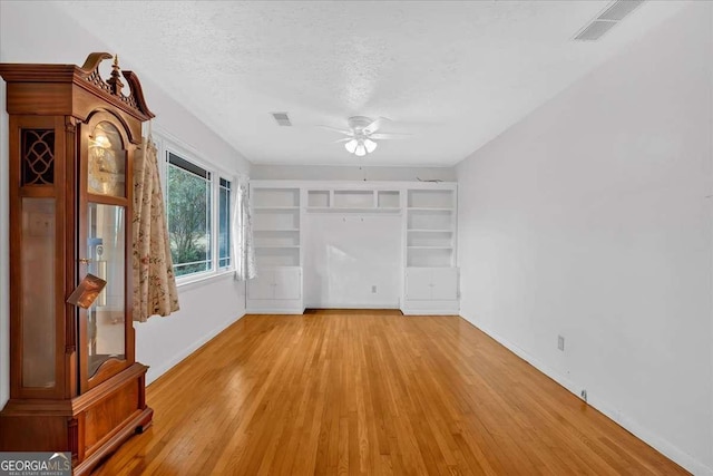 interior space featuring ceiling fan, light wood-type flooring, and a textured ceiling