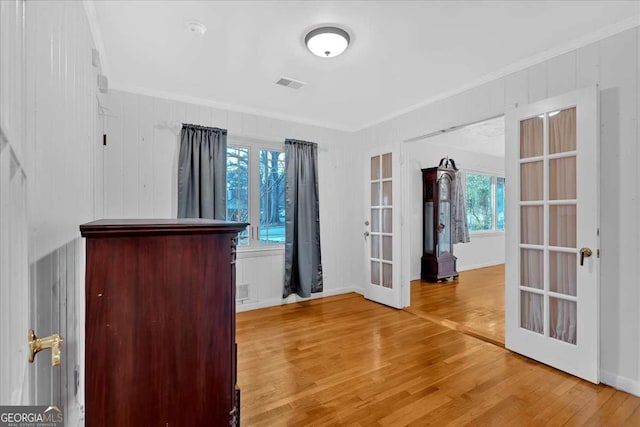 interior space with hardwood / wood-style floors, a healthy amount of sunlight, crown molding, and french doors