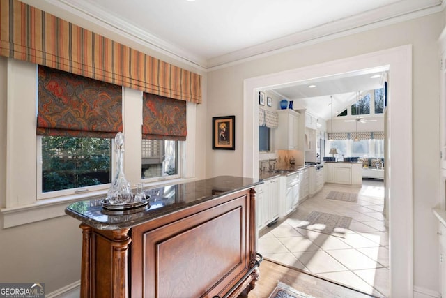 kitchen featuring ceiling fan, white cabinets, light tile patterned floors, and ornamental molding