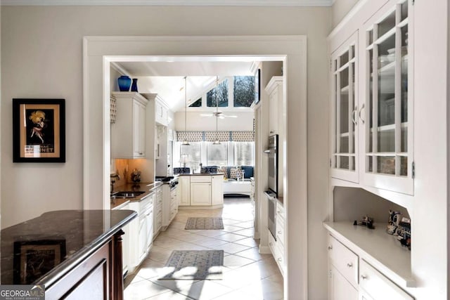 kitchen with white cabinets, light tile patterned floors, vaulted ceiling, and sink