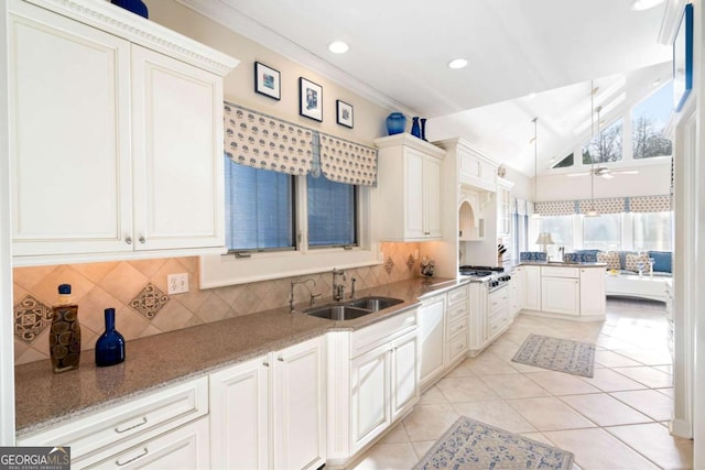 kitchen featuring decorative backsplash, sink, ceiling fan, and light stone countertops