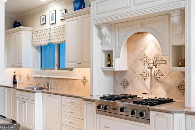 kitchen with backsplash, sink, ornamental molding, light stone counters, and stainless steel gas cooktop