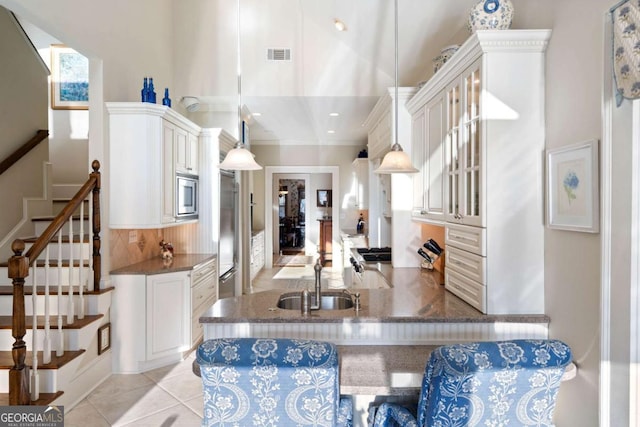 kitchen with sink, hanging light fixtures, kitchen peninsula, decorative backsplash, and appliances with stainless steel finishes