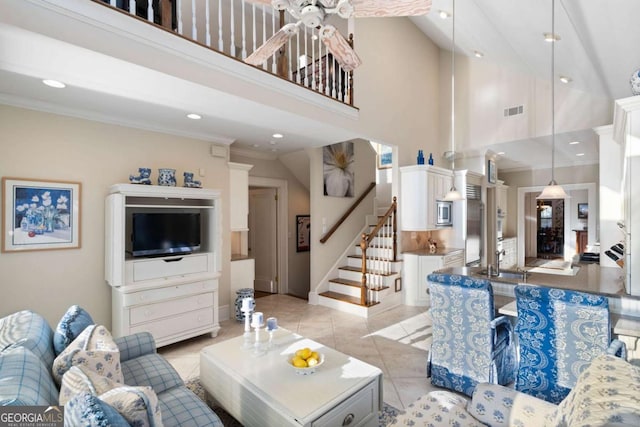 living room with a towering ceiling, ornamental molding, ceiling fan, sink, and light tile patterned floors