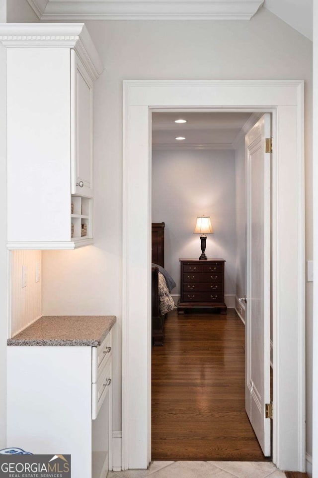 hallway with dark hardwood / wood-style flooring, vaulted ceiling, and ornamental molding