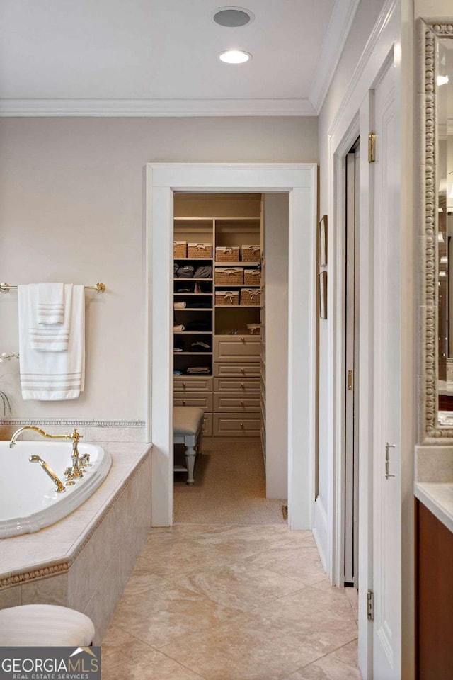 bathroom featuring tile patterned flooring, vanity, crown molding, and tiled tub