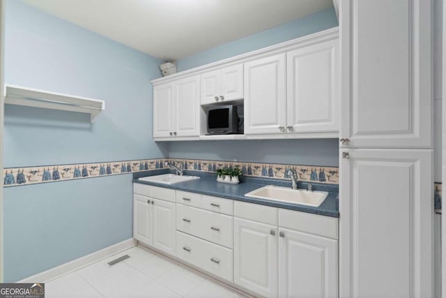 kitchen featuring white cabinetry, sink, and light tile patterned floors