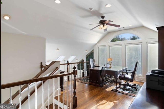 office space featuring dark hardwood / wood-style flooring, a wealth of natural light, vaulted ceiling with skylight, and ceiling fan