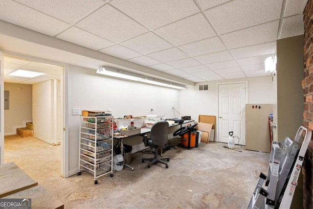 office with a paneled ceiling and concrete floors