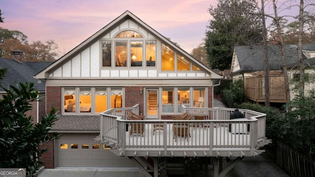 back house at dusk with a garage and a wooden deck