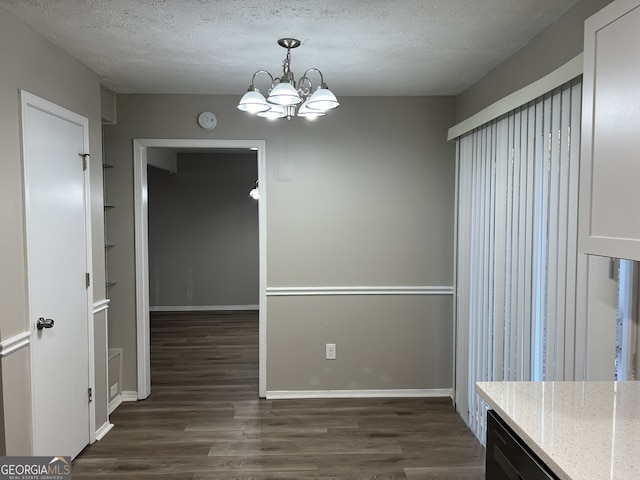 unfurnished dining area with a textured ceiling, dark wood-type flooring, and a chandelier