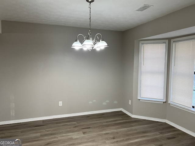 empty room with dark hardwood / wood-style flooring, a textured ceiling, and a chandelier