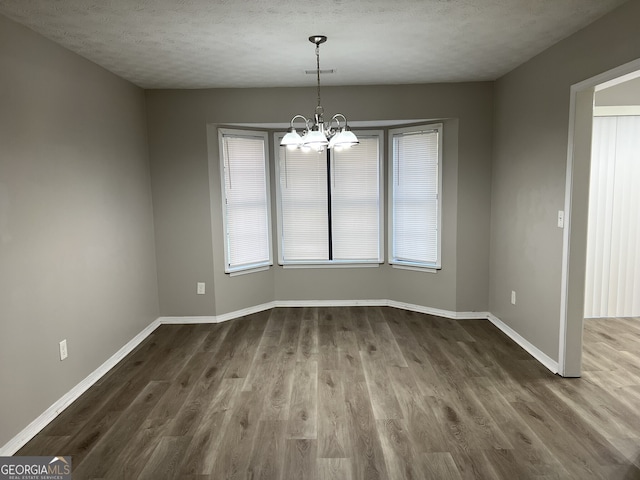 unfurnished room featuring wood-type flooring, a textured ceiling, and an inviting chandelier