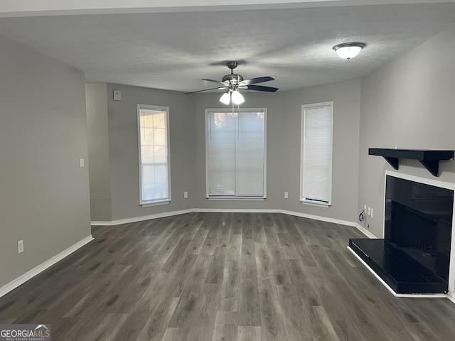 unfurnished living room featuring a textured ceiling, ceiling fan, and dark wood-type flooring