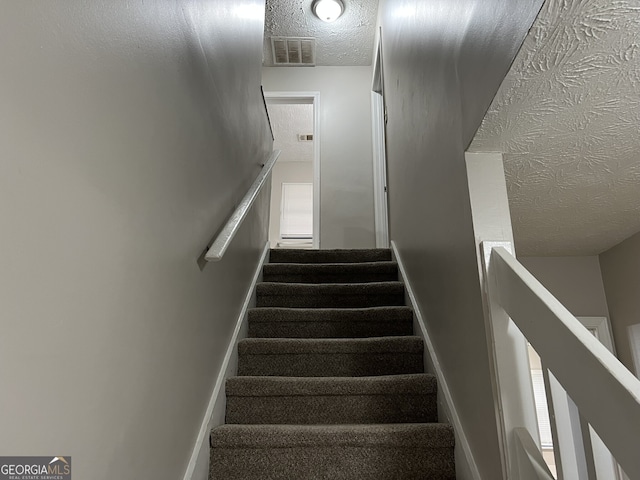 staircase featuring a textured ceiling