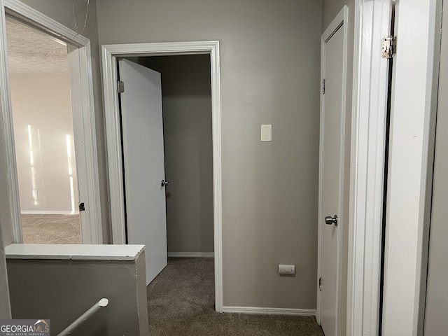 hall with dark colored carpet