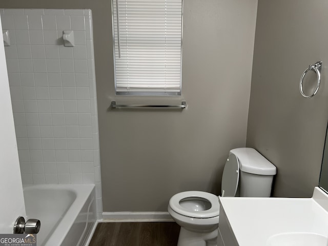 full bathroom with tiled shower / bath, hardwood / wood-style floors, vanity, and toilet