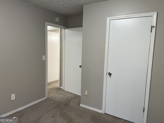 unfurnished bedroom with dark colored carpet and a textured ceiling