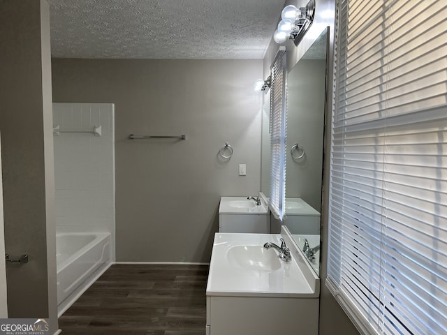 bathroom featuring vanity, a textured ceiling, hardwood / wood-style flooring, and a tub