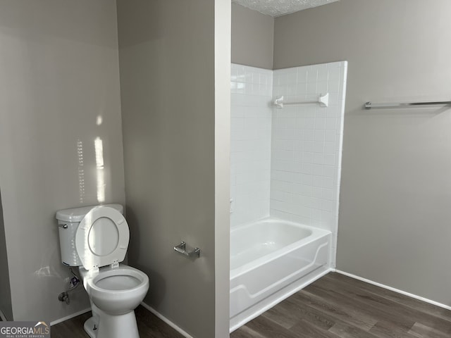 bathroom with shower / bathing tub combination, a textured ceiling, hardwood / wood-style flooring, and toilet