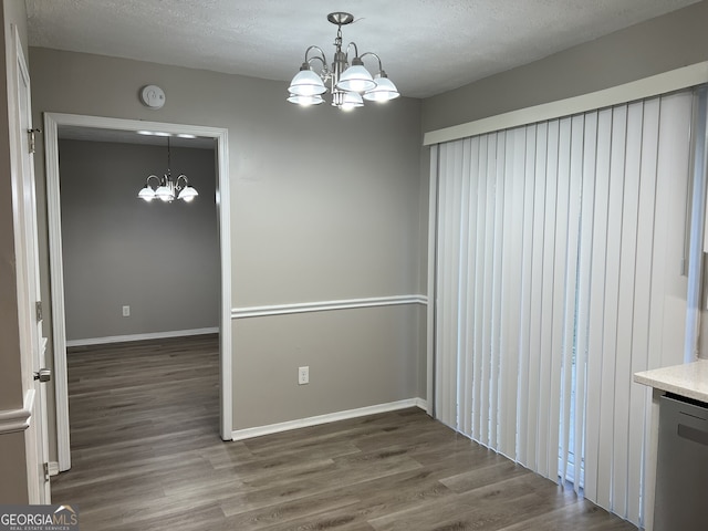 unfurnished dining area with dark hardwood / wood-style flooring, a textured ceiling, and a chandelier