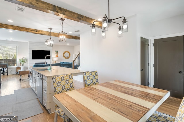 dining space featuring beam ceiling, an inviting chandelier, light hardwood / wood-style flooring, and sink